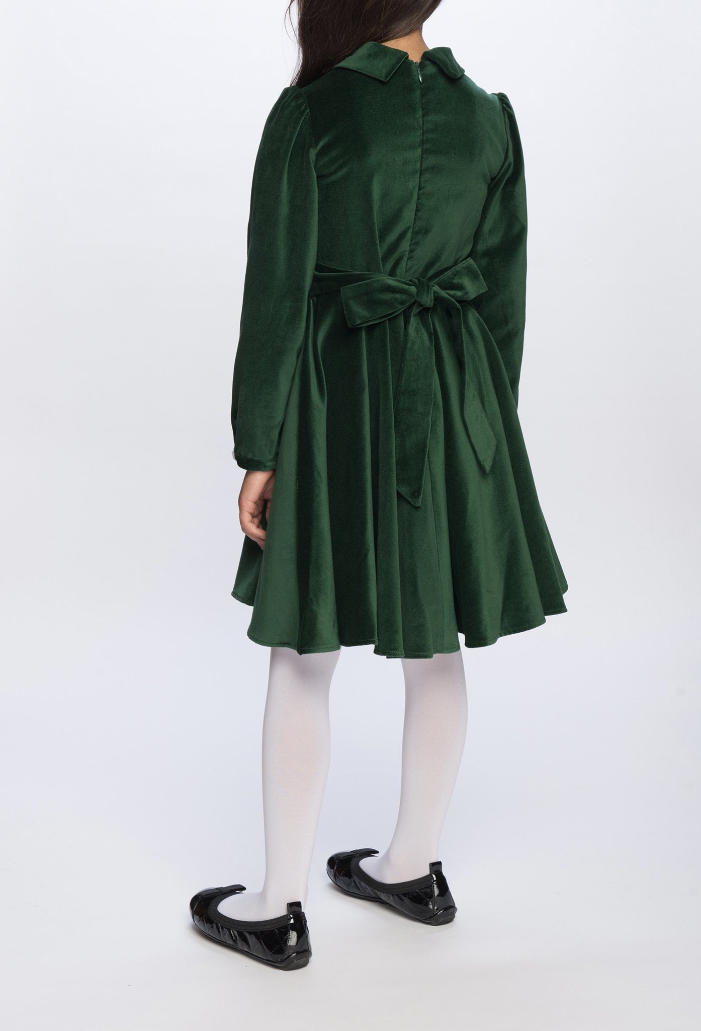 A girl standing in a green velvet dress.