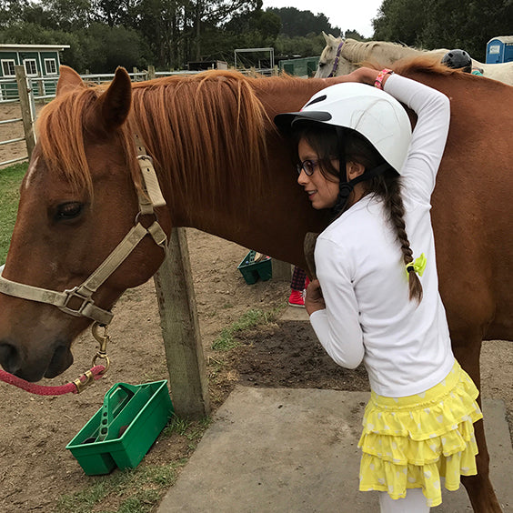 Founder's daughter hugging a horse at camp