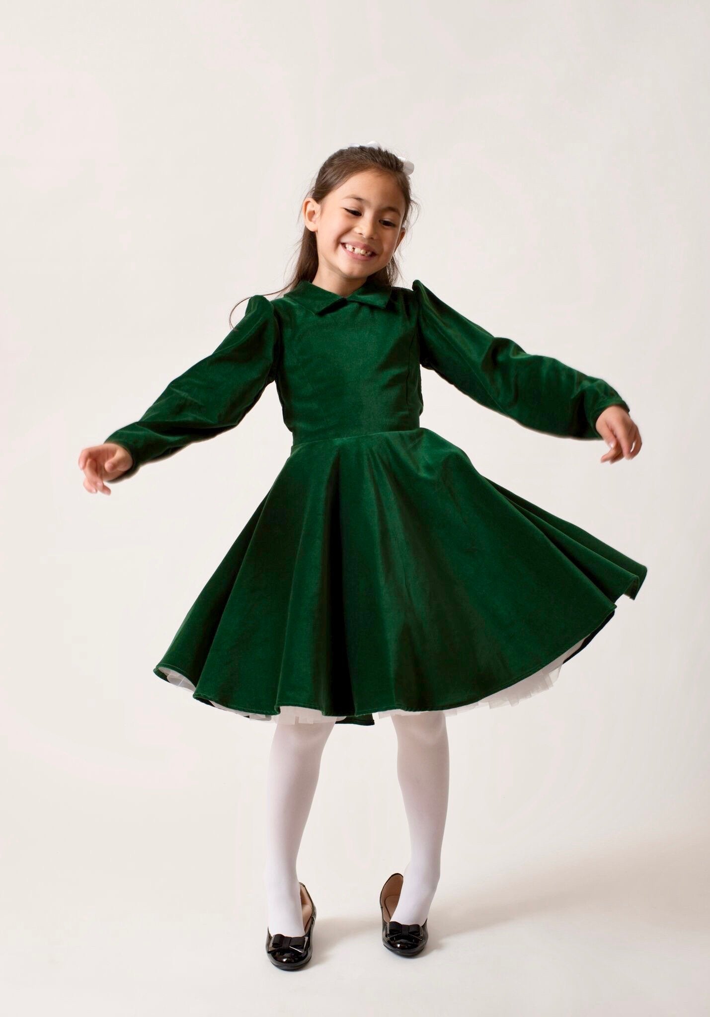 A girl jumping in a green velvet dress.