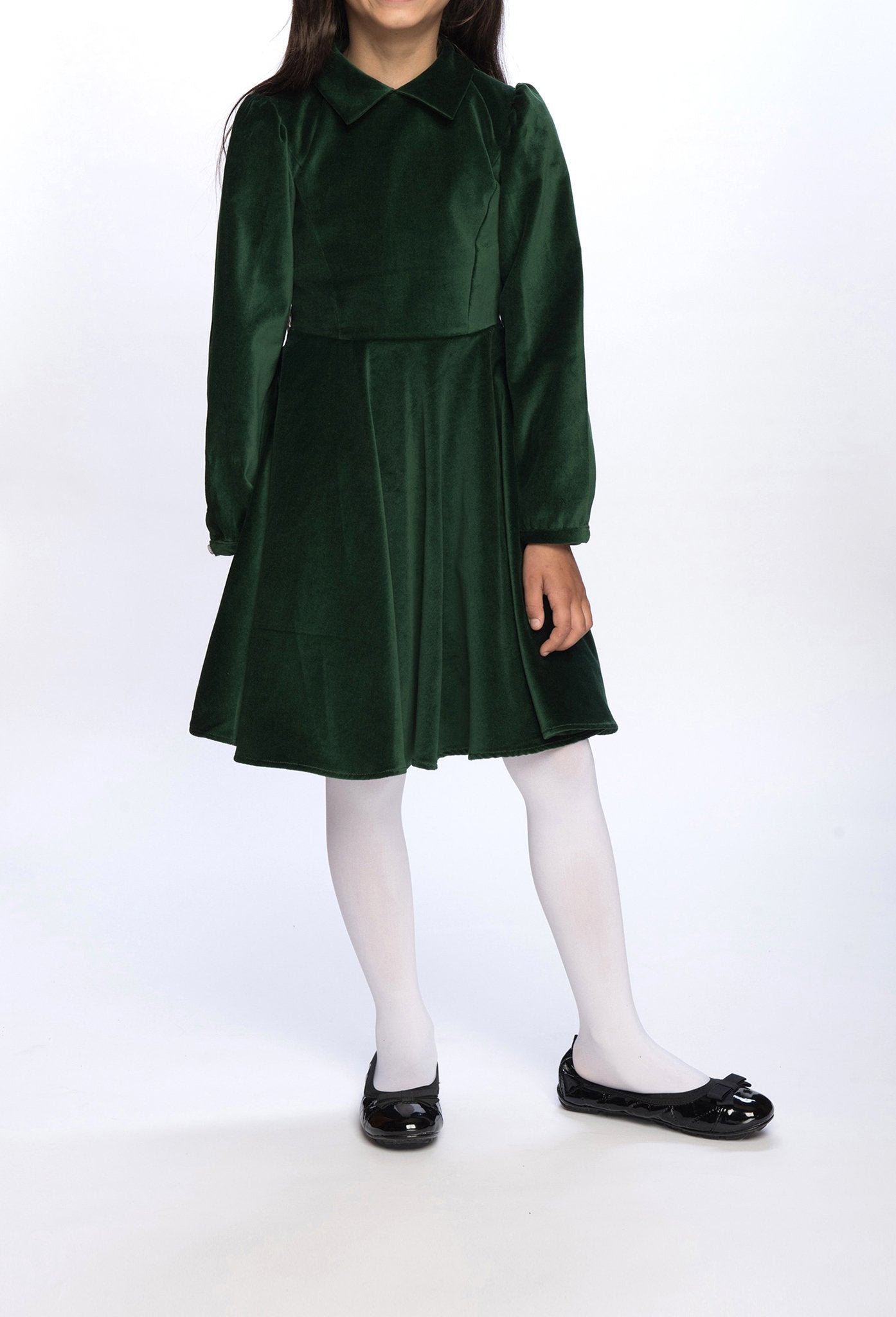 A girl standing in a green velvet dress.
