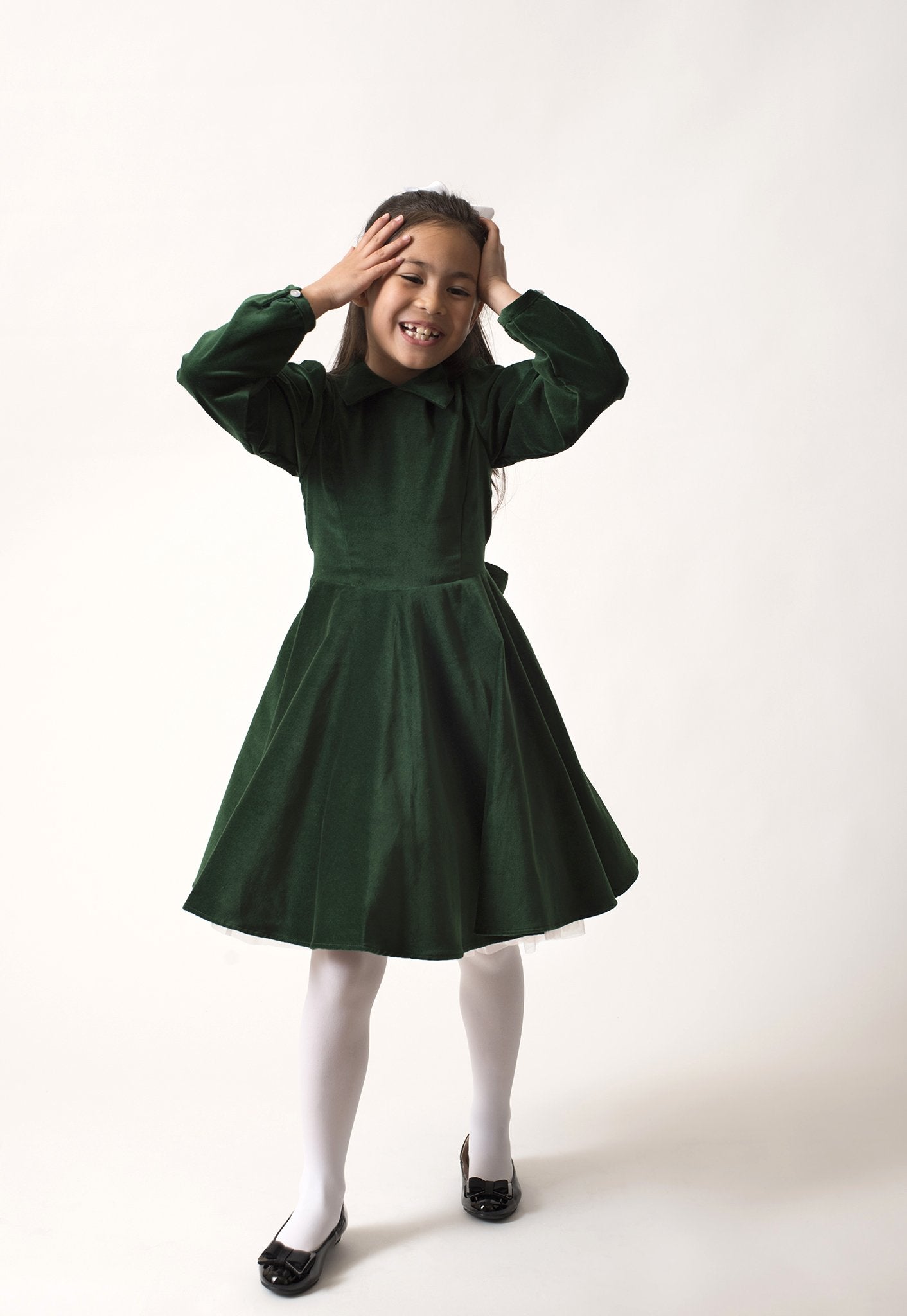 A girl standing in a green velvet dress.