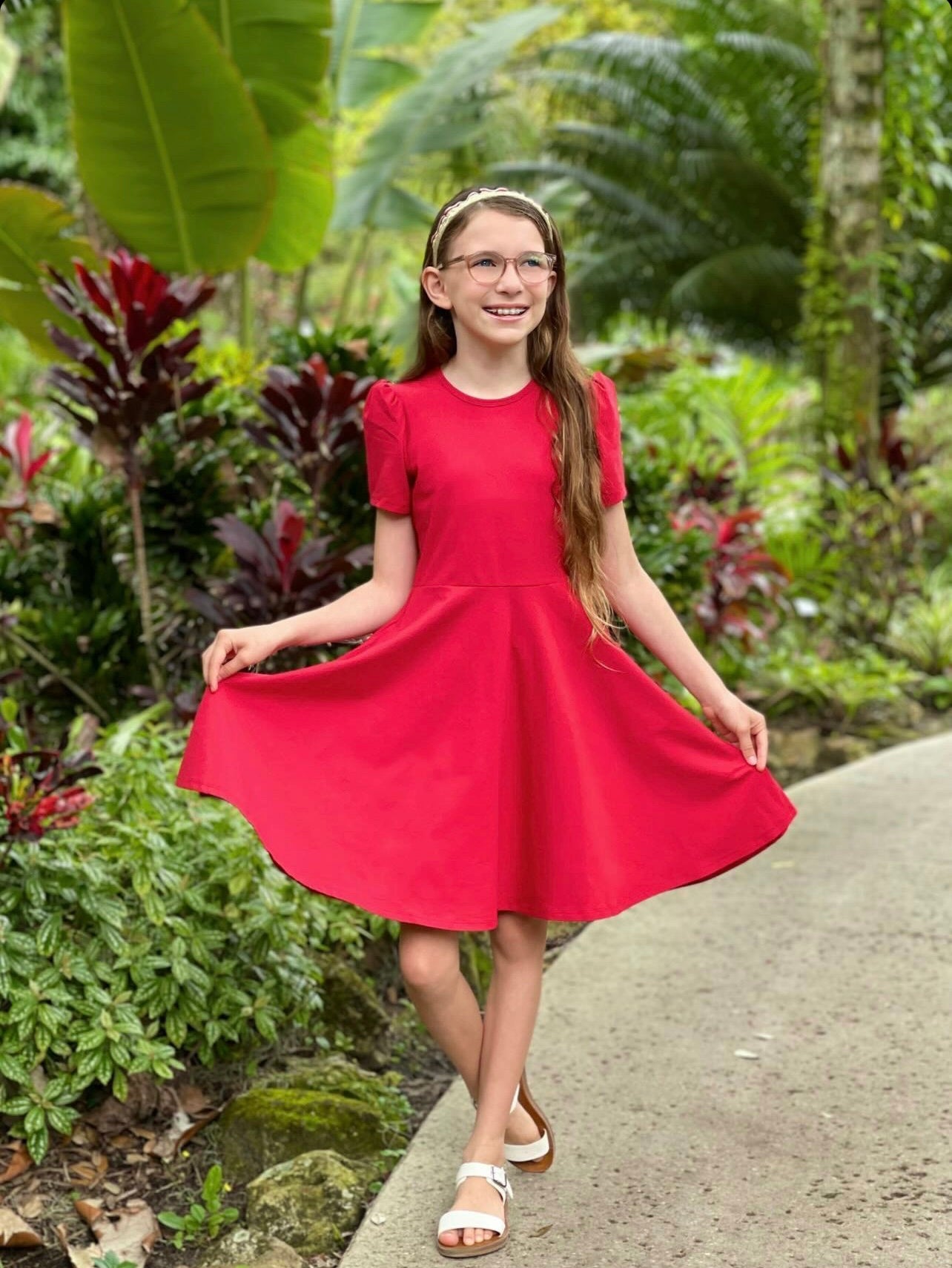Girl posing in a red dress in a garden.