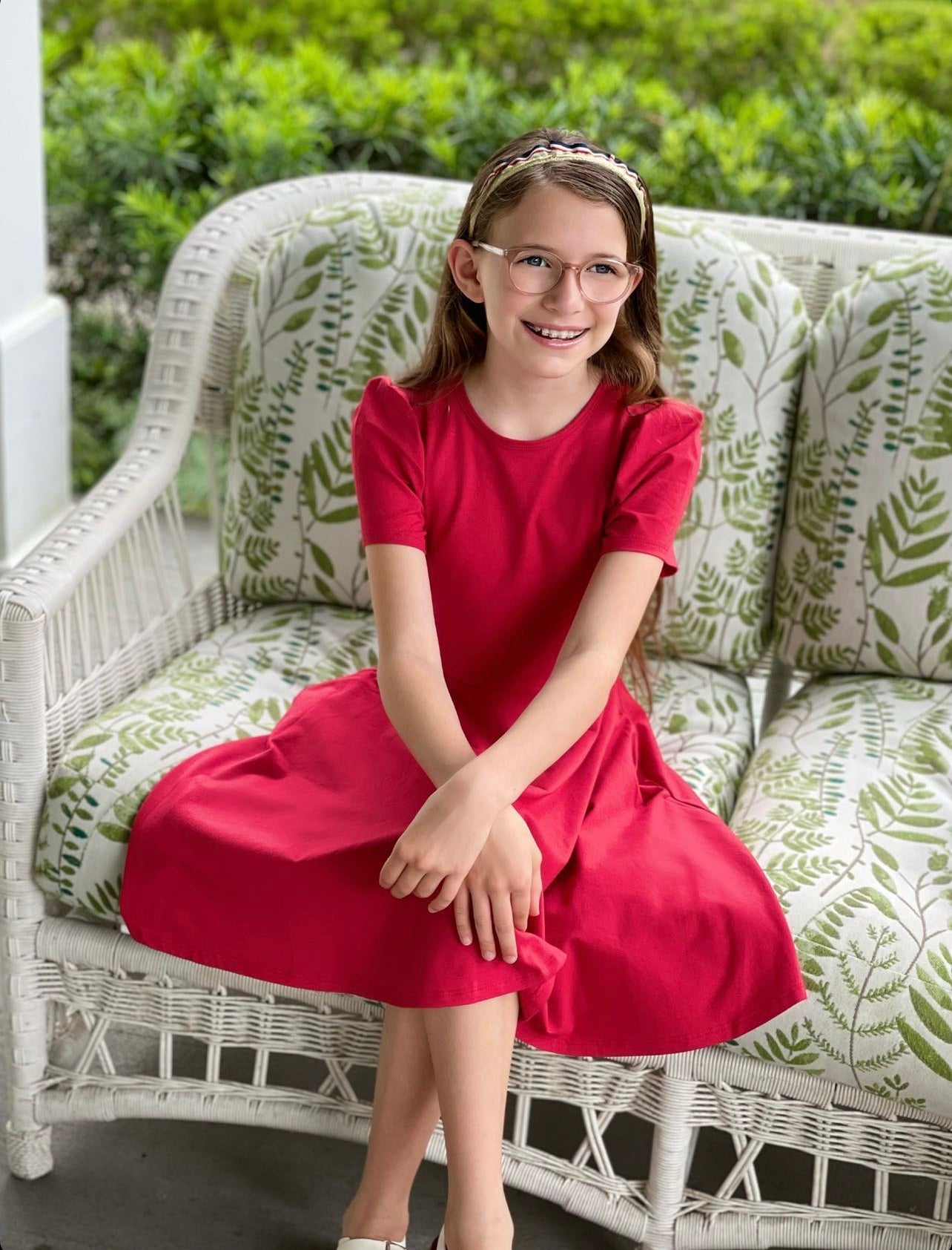 Little girl sitting on a chair in a red dress.